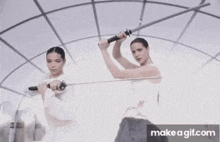 two women are holding swords in front of a mirror .