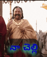 a man with a mustache is standing in front of a sign that says ' na chali ' on it
