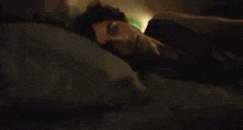 a man is laying on a bed with his eyes closed and his head on a pillow .