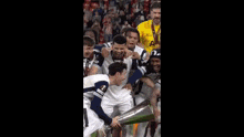 a group of soccer players are holding a trophy and one of them is wearing a shirt with the letter a on it