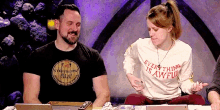 a man wearing a shirt that says " everything is awful " sits next to a woman