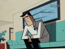 a man in a suit and tie is sitting on a couch looking out a window .