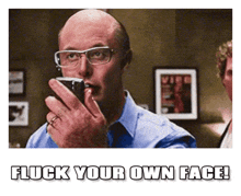 a man with glasses is holding a cell phone in his mouth and the caption says flick your own face