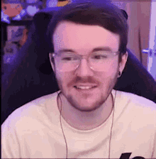 a man wearing glasses and headphones is sitting in a chair and smiling .