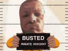 a man is holding up a busted inmate # 0312847 sign