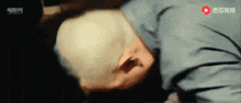 a man with a bald head is laying down in a dark room ..