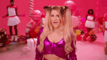 a woman with pigtails is wearing a purple crop top and a necklace