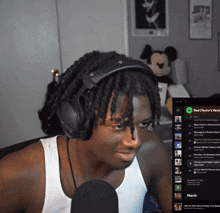 a man wearing headphones and a white tank top is listening to red taylor 's version