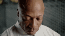 a bald man in a white shirt and tie is looking down .