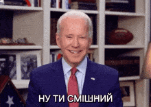 a man in a suit and tie is smiling in front of a bookshelf and says ну ти смішний