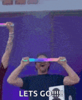 a man is holding a light stick in front of his face and says lets go !!!