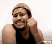 a man wearing a hat is making a funny face .