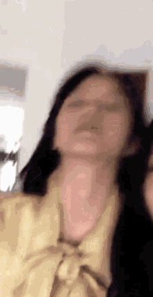 a woman in a yellow shirt is making a funny face