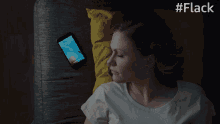 a woman laying on a couch next to a cell phone that says 12:58 on the screen