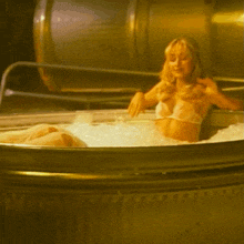 a woman in a bikini is laying in a tub of ice