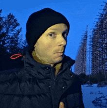 a man wearing a black hat and a black jacket stands in the snow