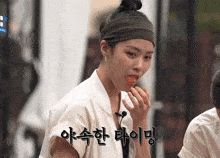 a woman wearing a headband is eating something with korean writing on her face