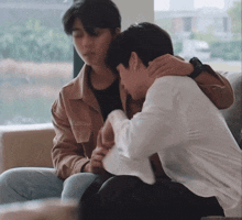 a man in a brown jacket is hugging another man