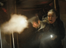 a woman is holding a flashlight and pointing a gun at a man