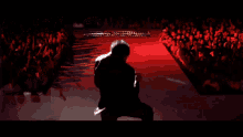 a man in a suit stands on a stage in front of a crowd of people