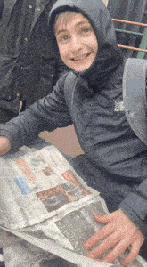 a boy wearing a karrimor hooded jacket is looking at a newspaper