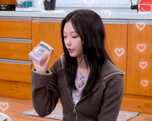a woman in a brown jacket is holding a pink box