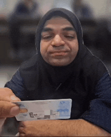a man with a hijab on his head is holding a passport