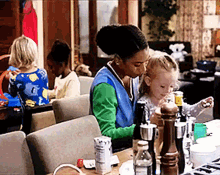 a woman is sitting at a table with a child and a bottle of water
