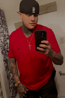 a man in a red shirt is taking a picture of himself
