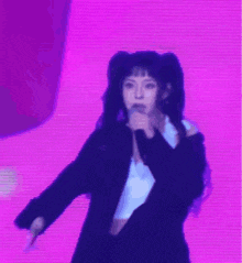 a girl with pigtails is singing into a microphone on a purple background .