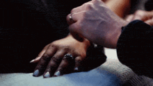 a man is holding a woman 's hand with a wedding ring on it .