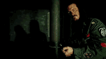 a man in a green jacket is handcuffed to a pole .
