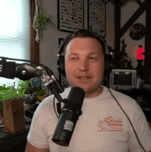 a man wearing headphones stands in front of a microphone with a shirt that says columbia on it