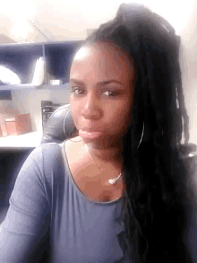 a woman with dreadlocks looks at the camera with a serious look on her face