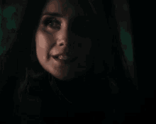 a close up of a woman 's face in the dark with a green background