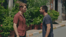 a man with red hair is hugging another man with dark hair