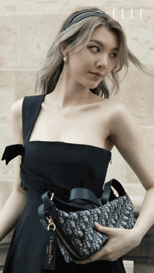 a woman in a black dress is holding a bag that says christian dior on it