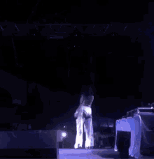 a person is dancing in a dark room with a light behind them