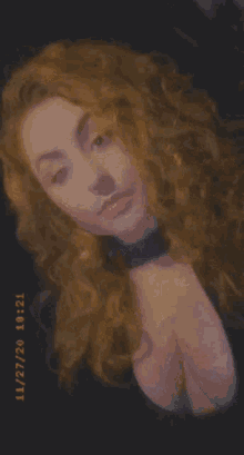 a woman with curly hair is smiling and wearing a choker collar