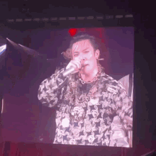 a man is singing into a microphone while wearing a necklace