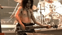a man without a shirt is playing a guitar on stage .