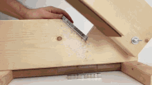 a person is holding a piece of wood that has a metal piece on it