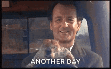 a man is driving a car and holding a groundhog in his lap .