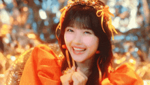 a girl wearing an orange dress and a tiara smiles