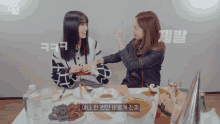 two women sitting at a table with a twice logo on the bottom