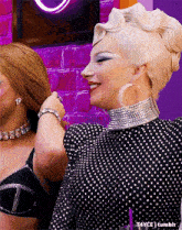 a woman in a polka dot dress is holding another woman 's hair while smiling .