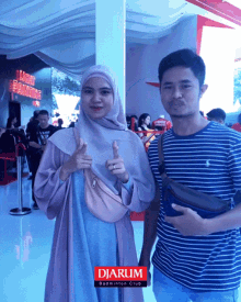 a man and a woman are posing for a photo in front of a sign that says " light fearssing "
