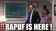 a man in a suit and tie is standing next to a woman in a purple shirt and says " rapuf is here "