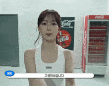 a woman is standing in front of a coca cola fridge