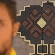 a close up of a person 's face with a geometric pattern on the wall